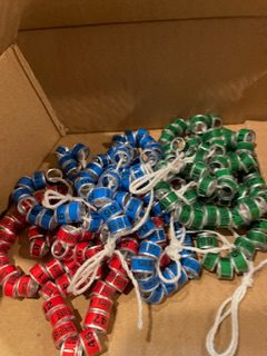 A box of soda cans with strings attached to them.