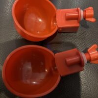 Two cups that are sitting on a table.|A pair of red cups sitting on top of a black table.