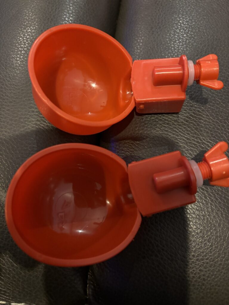 Two cups that are sitting on a table.|A pair of red cups sitting on top of a black table.