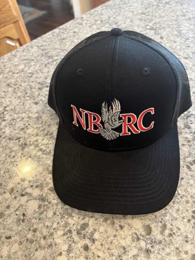 A black hat with the letters nbrc on it|A black hat sitting on top of a counter.